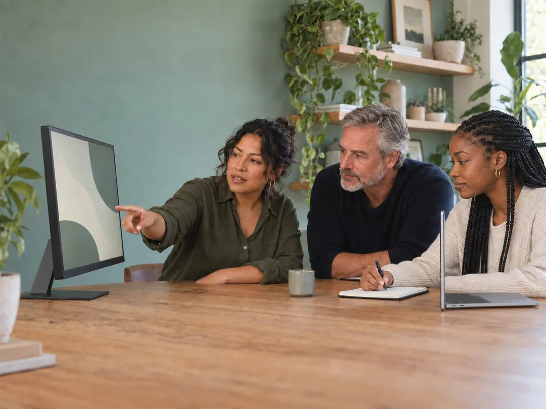 Web team discussing feedback around a monitor